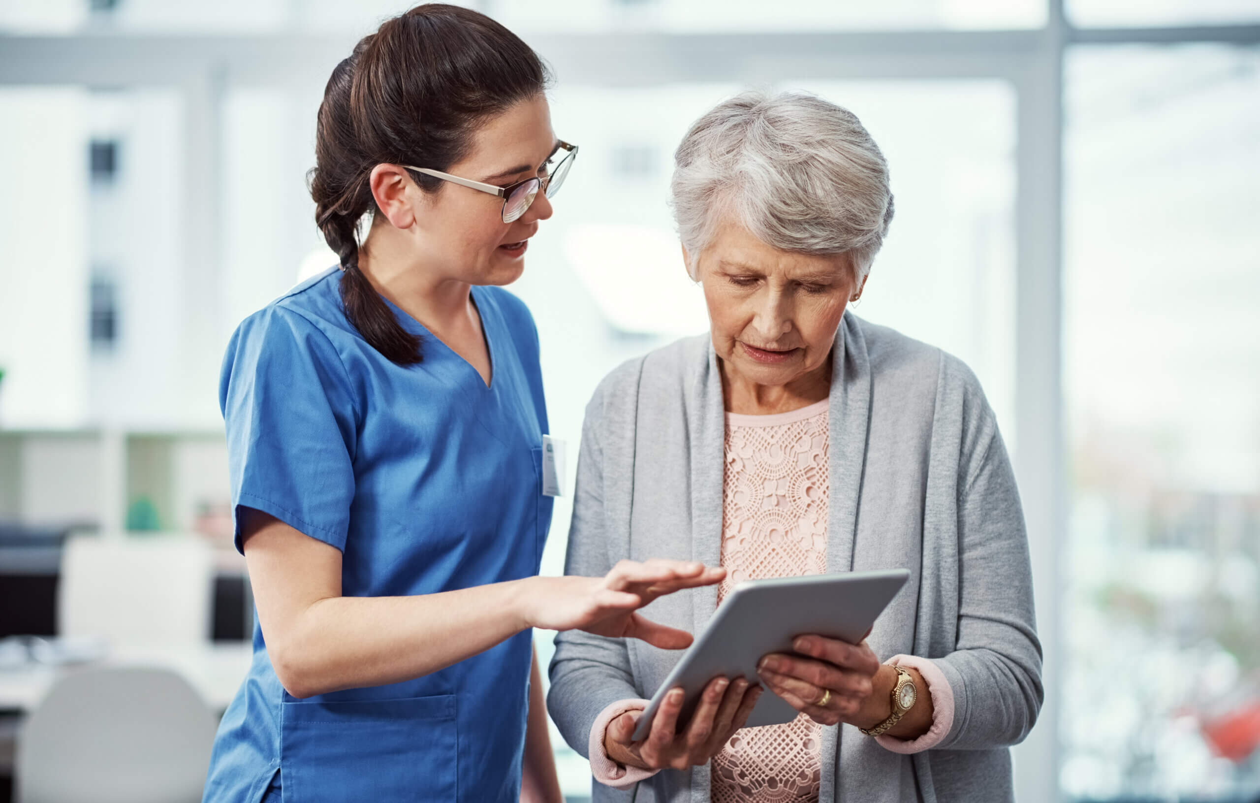 A nurse and a senior woman looking at a tablet